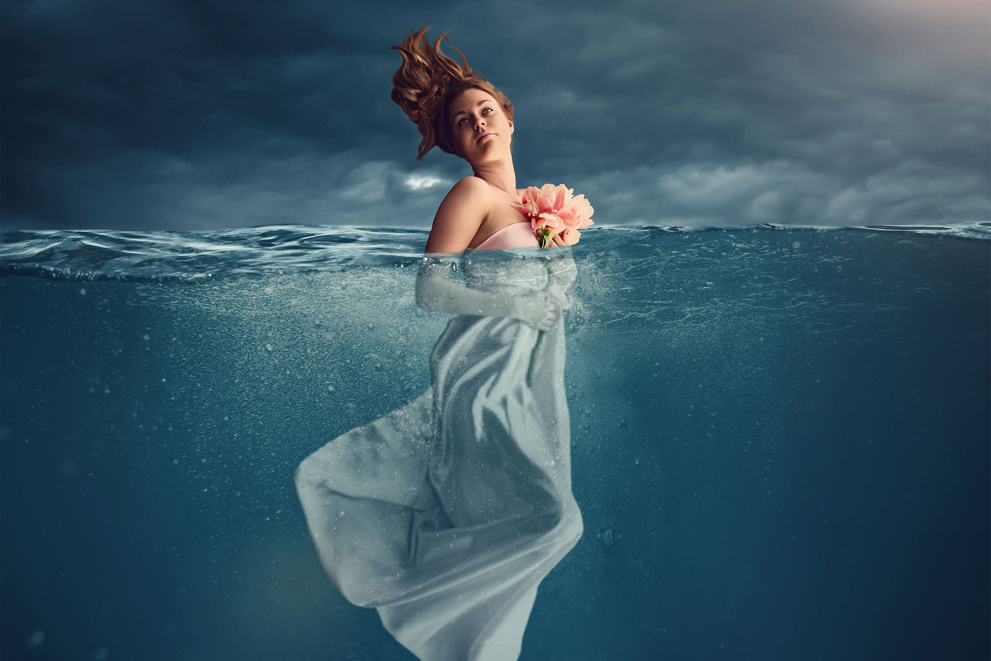 En kreativ bild på en kvinna halvt under vatten.